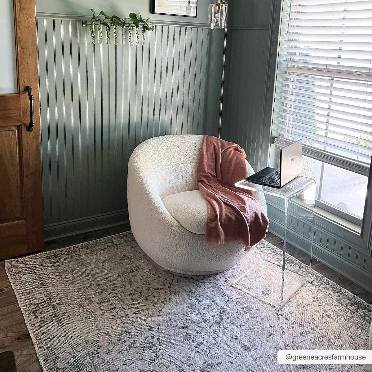 White armchair with a pink blanket in a room with a window and decorative elements.