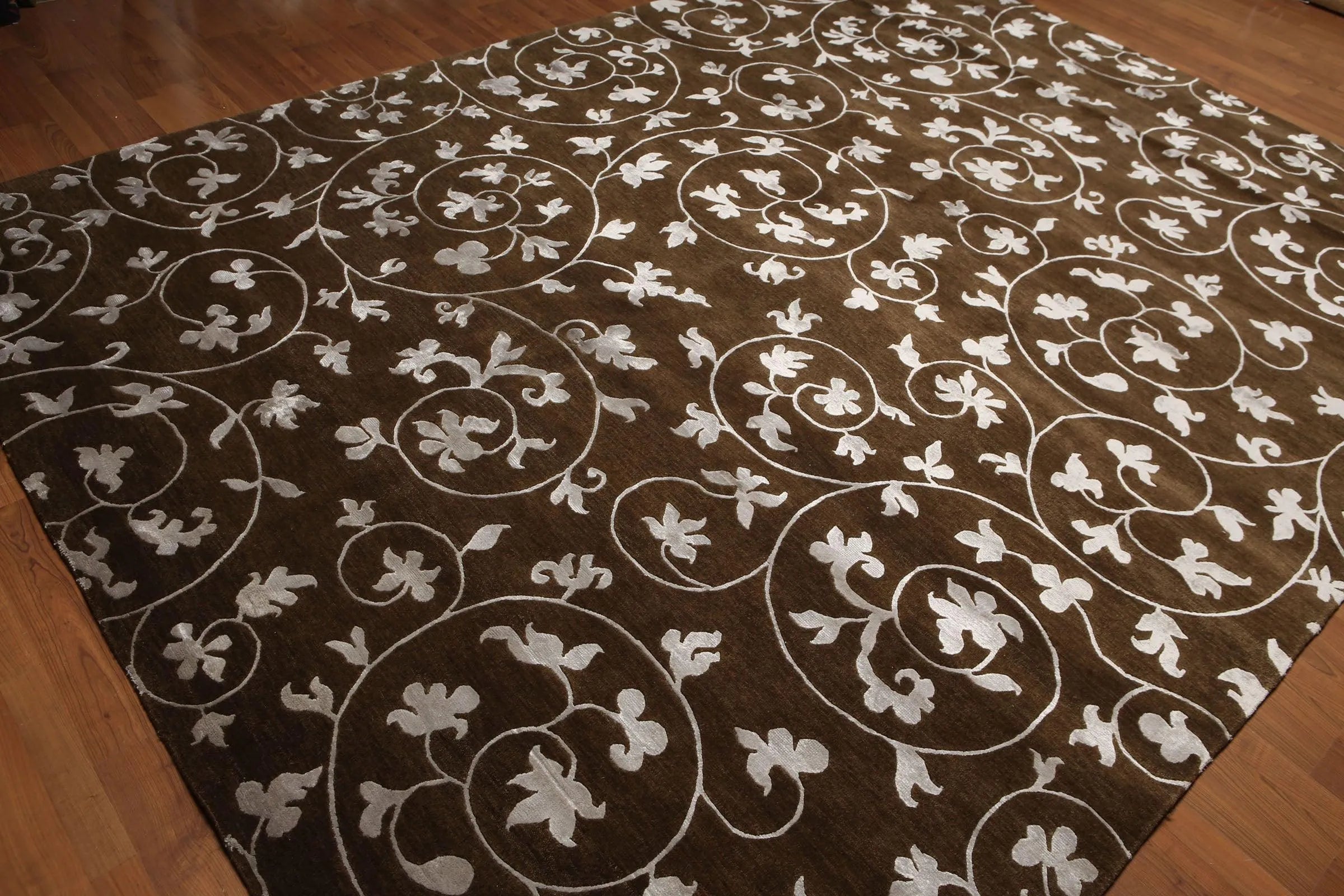 Brown rug with white floral patterns on a wooden floor