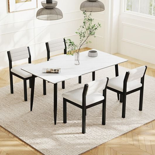 Dining room set with a white table and black chairs on a wooden floor.