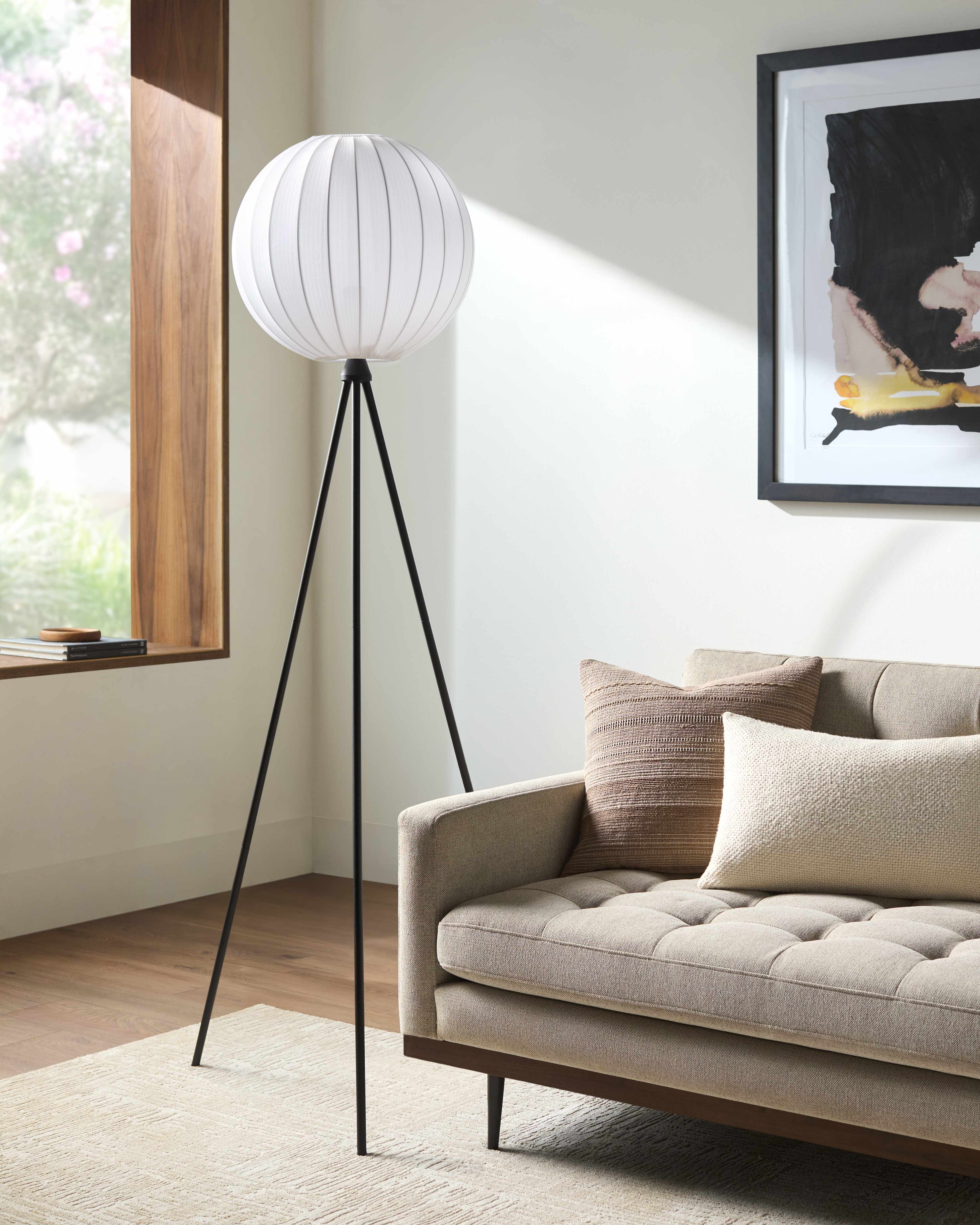 Modern living room with a tripod floor lamp and beige sofa.