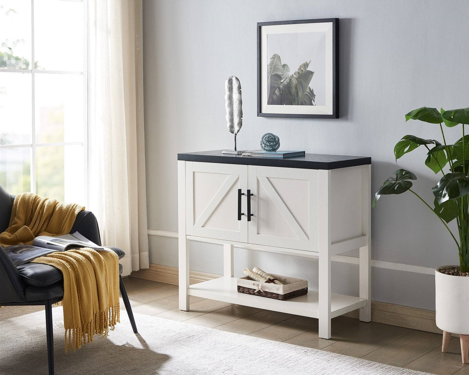 White cabinet with black countertop in a room with a chair, plant, and framed picture.