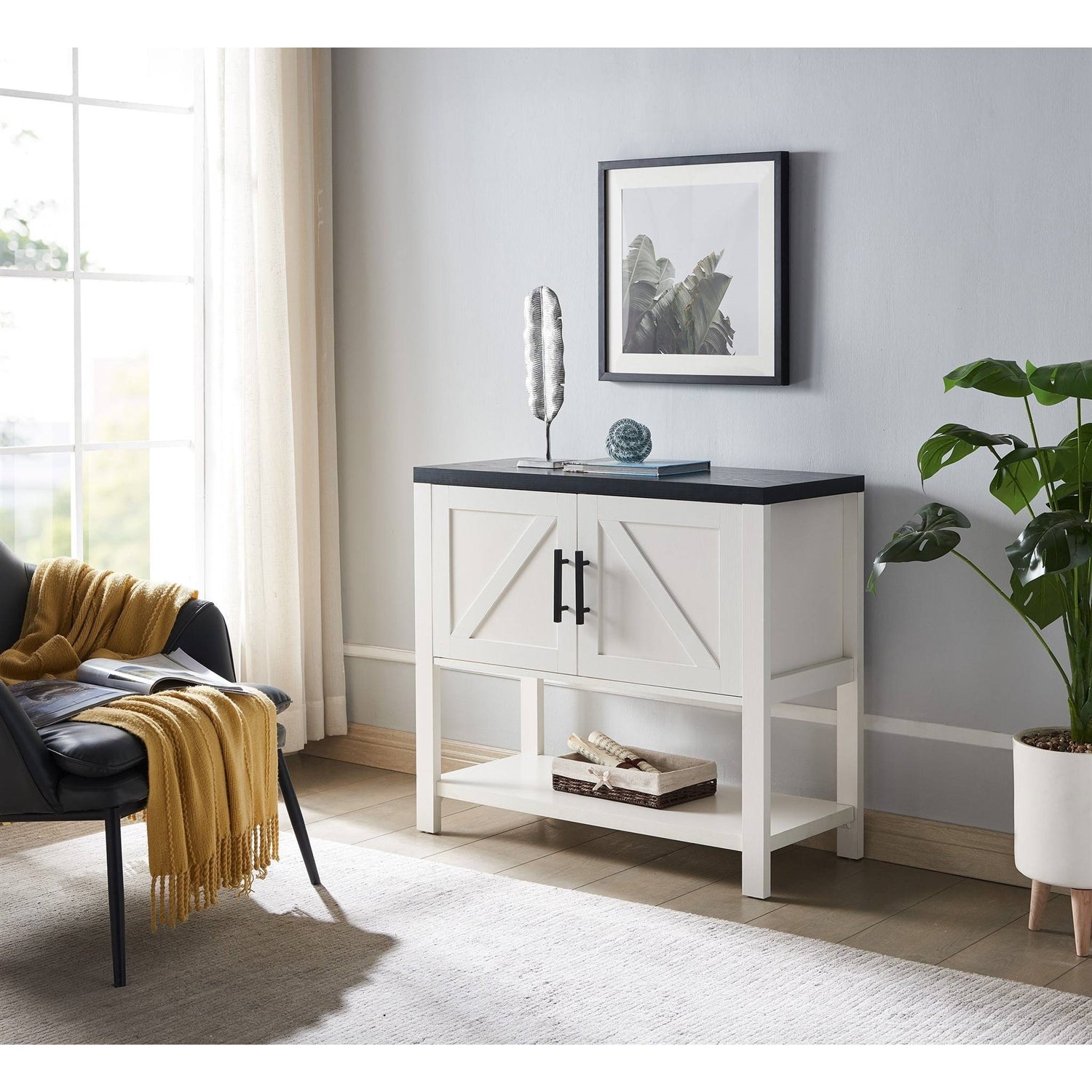 White cabinet with black countertop in a room with a chair, plant, and framed picture.