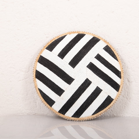 Round black and white striped cushion with a wooden border on a light background