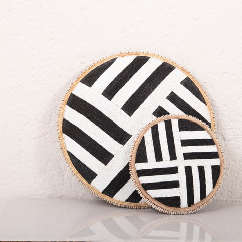 Two circular coasters with black and white geometric pattern on a textured surface