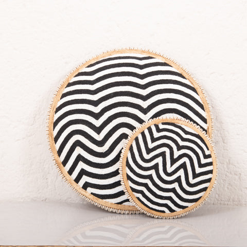 Two round coasters with black and white zigzag pattern on a textured surface