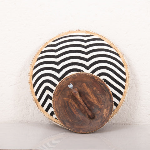 Round woven mat with black and white wavy pattern on a light background