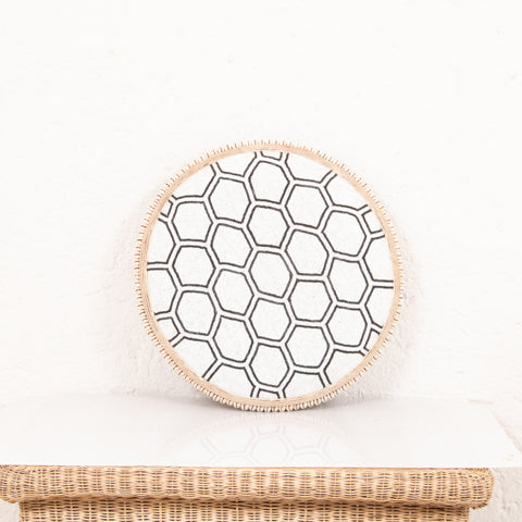 Round woven basket with a geometric pattern on a white background