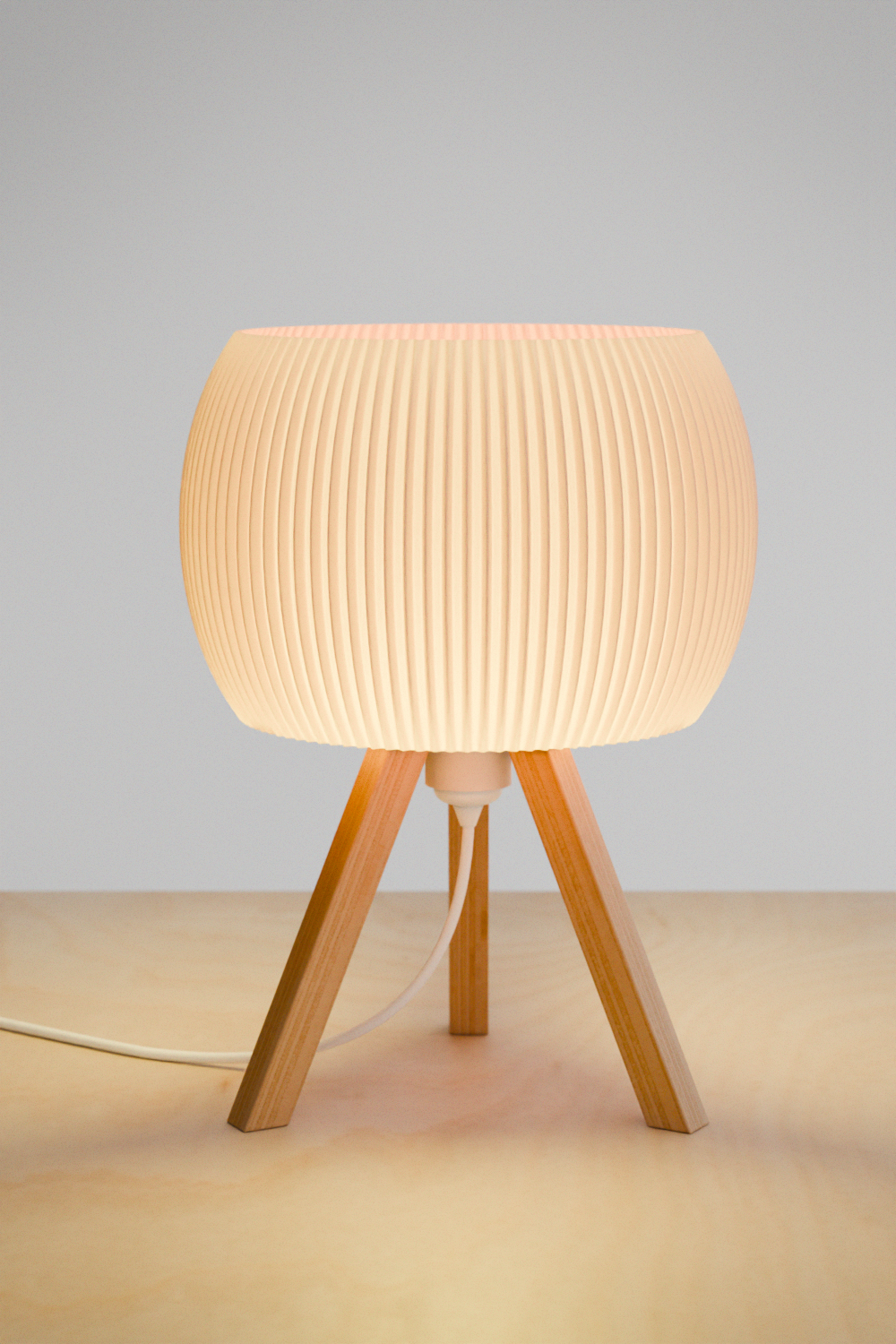 Table lamp with wooden base and ribbed white shade on a neutral background