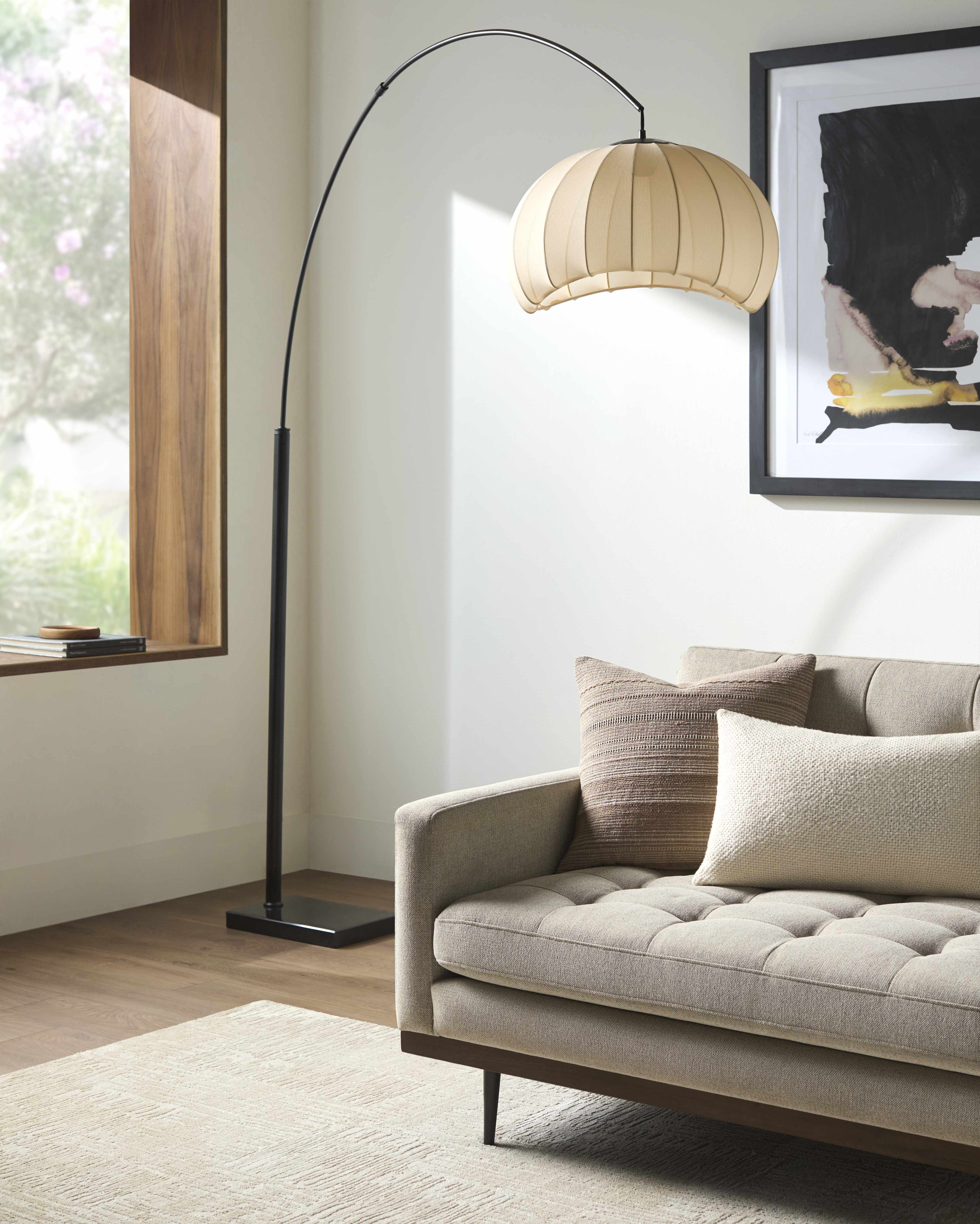 Modern living room with a gray sofa, floor lamp, and framed artwork.