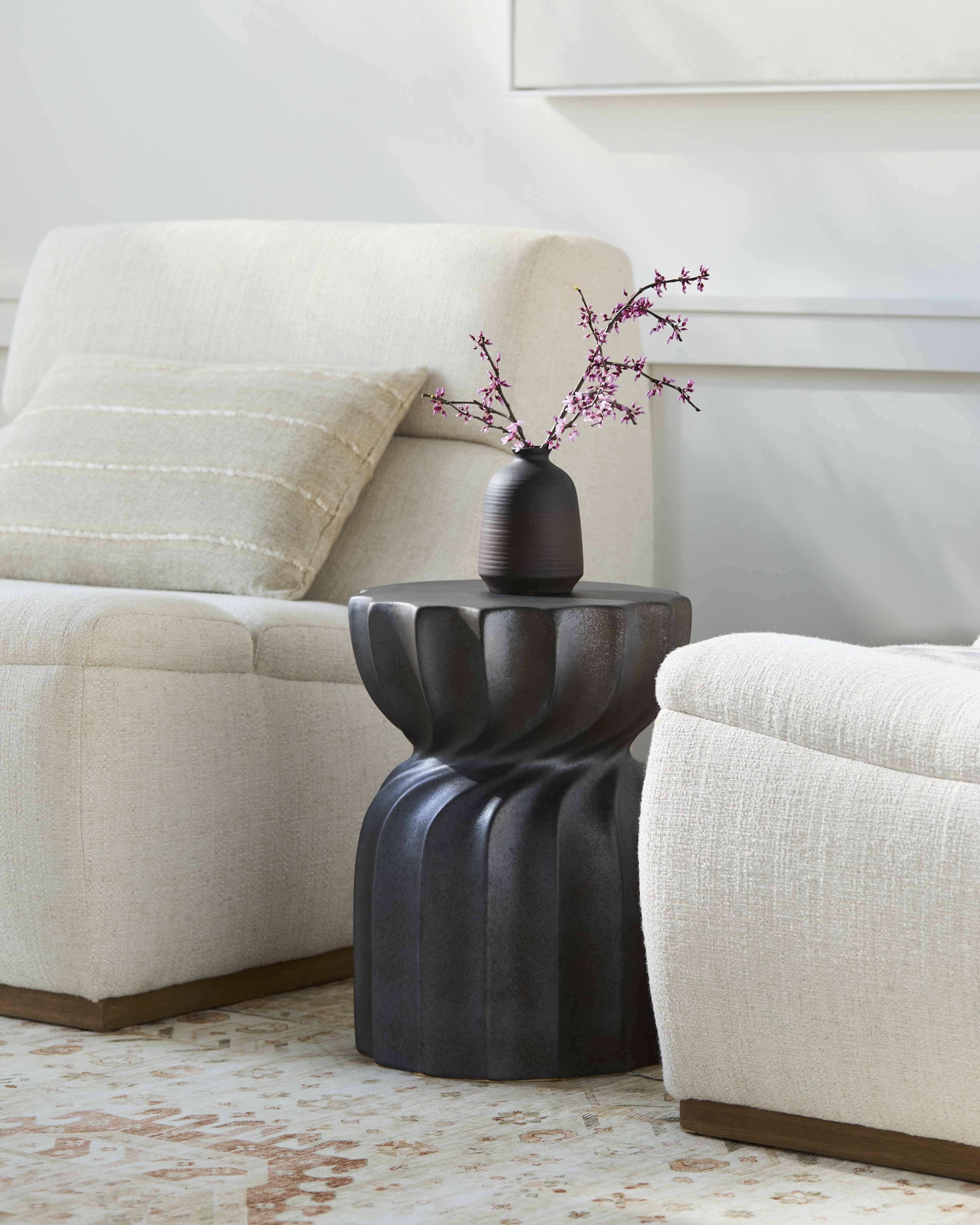 Black decorative table with a vase and branches in a living room setting
