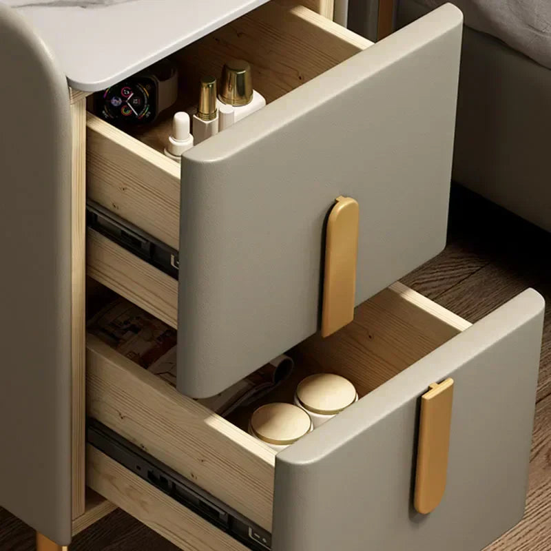 Open drawer of a modern nightstand with gold handles, containing various items.