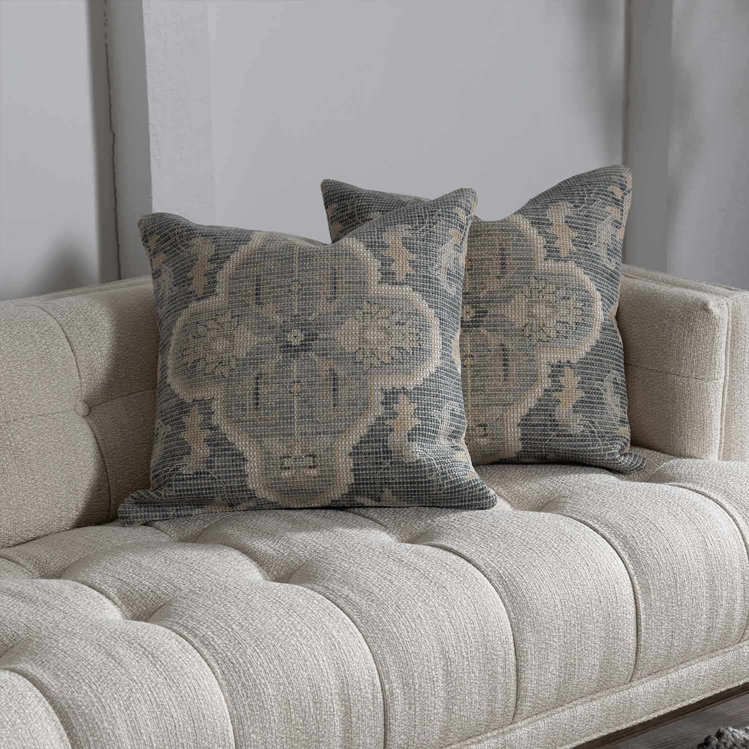 Decorative pillows with floral patterns on a beige sofa against a gray wall.
