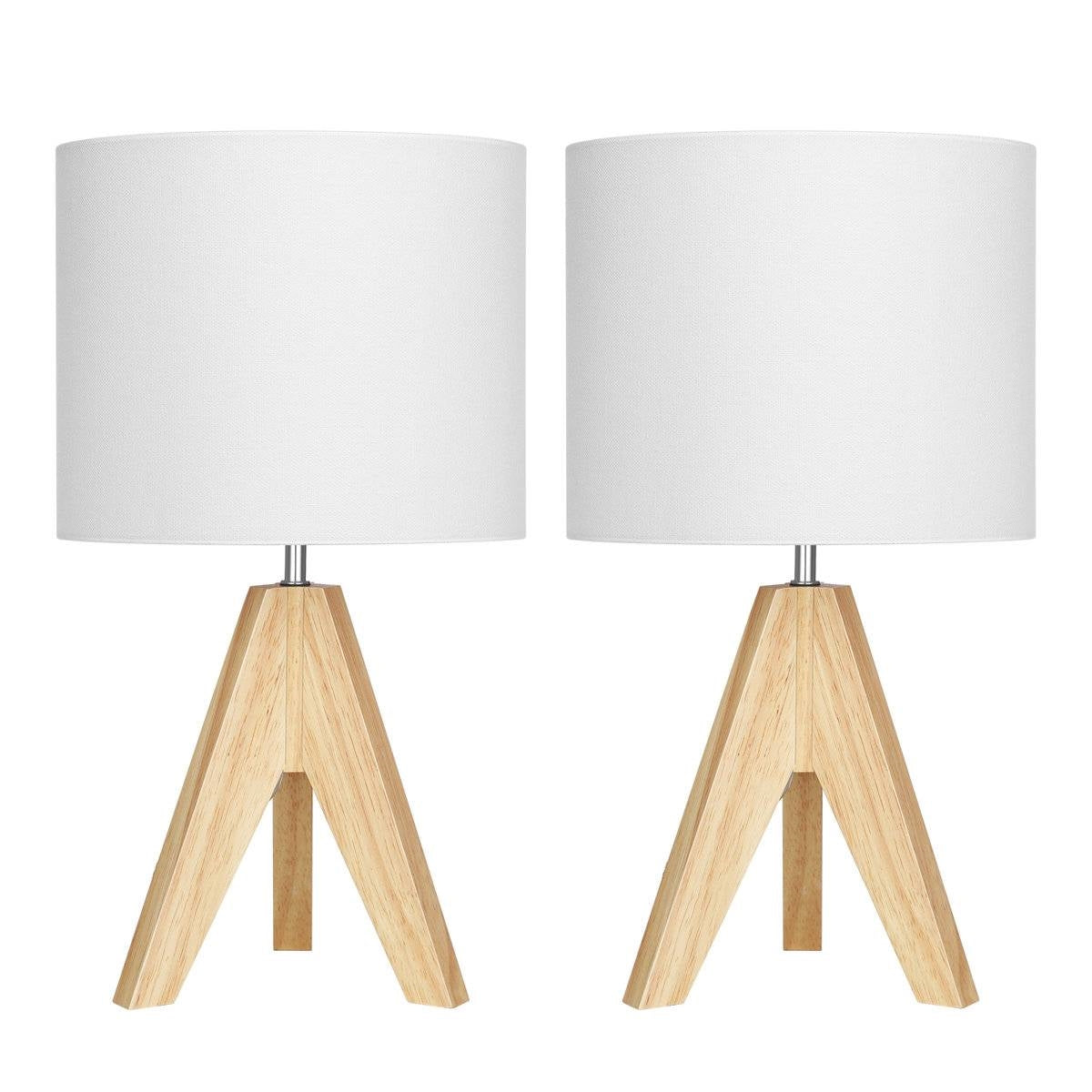 Two small table lamps with wooden bases on a surface, one on books and one on a flat surface.