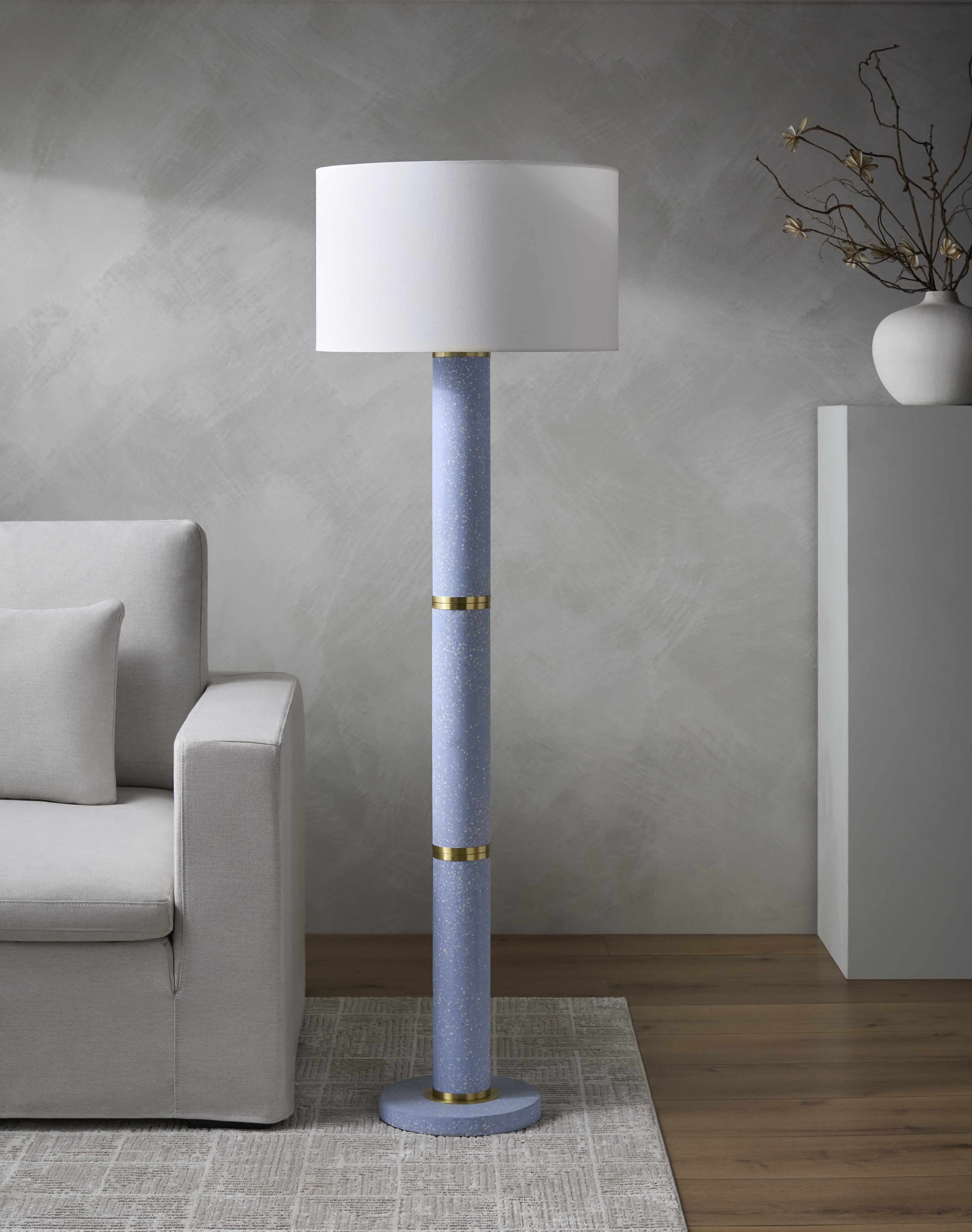 Floor lamp with a white shade and blue base in a living room setting.