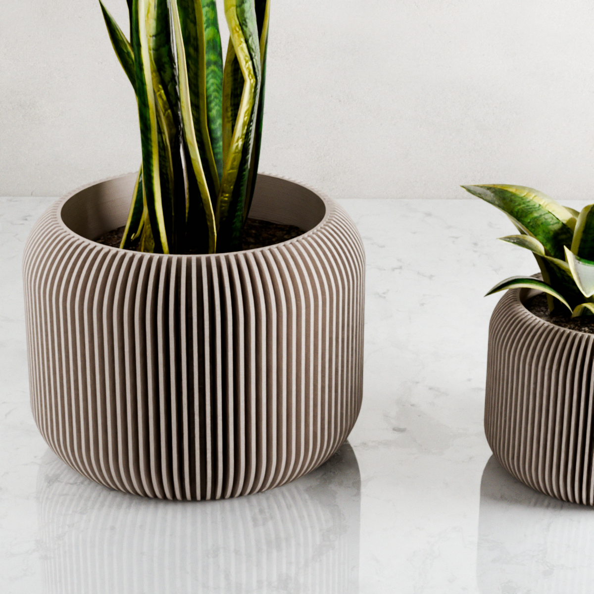 Two ribbed ceramic planters with plants on a light surface