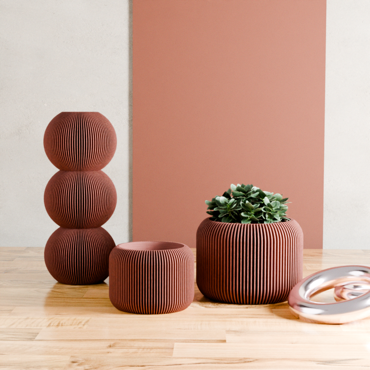Set of brown textured planters with a small green plant on a wooden surface against a pink wall.