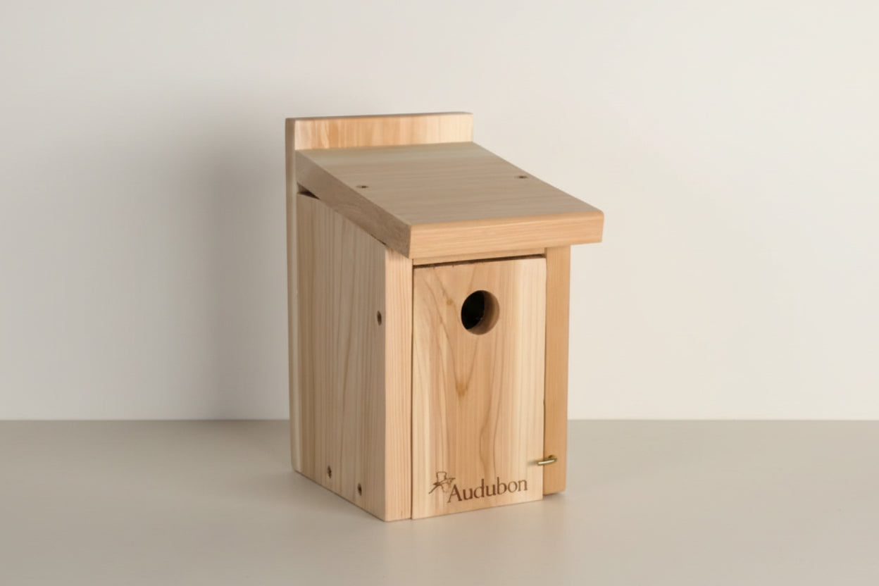 Wooden birdhouse with a small round entrance hole on a white background, featuring the Audubon logo.