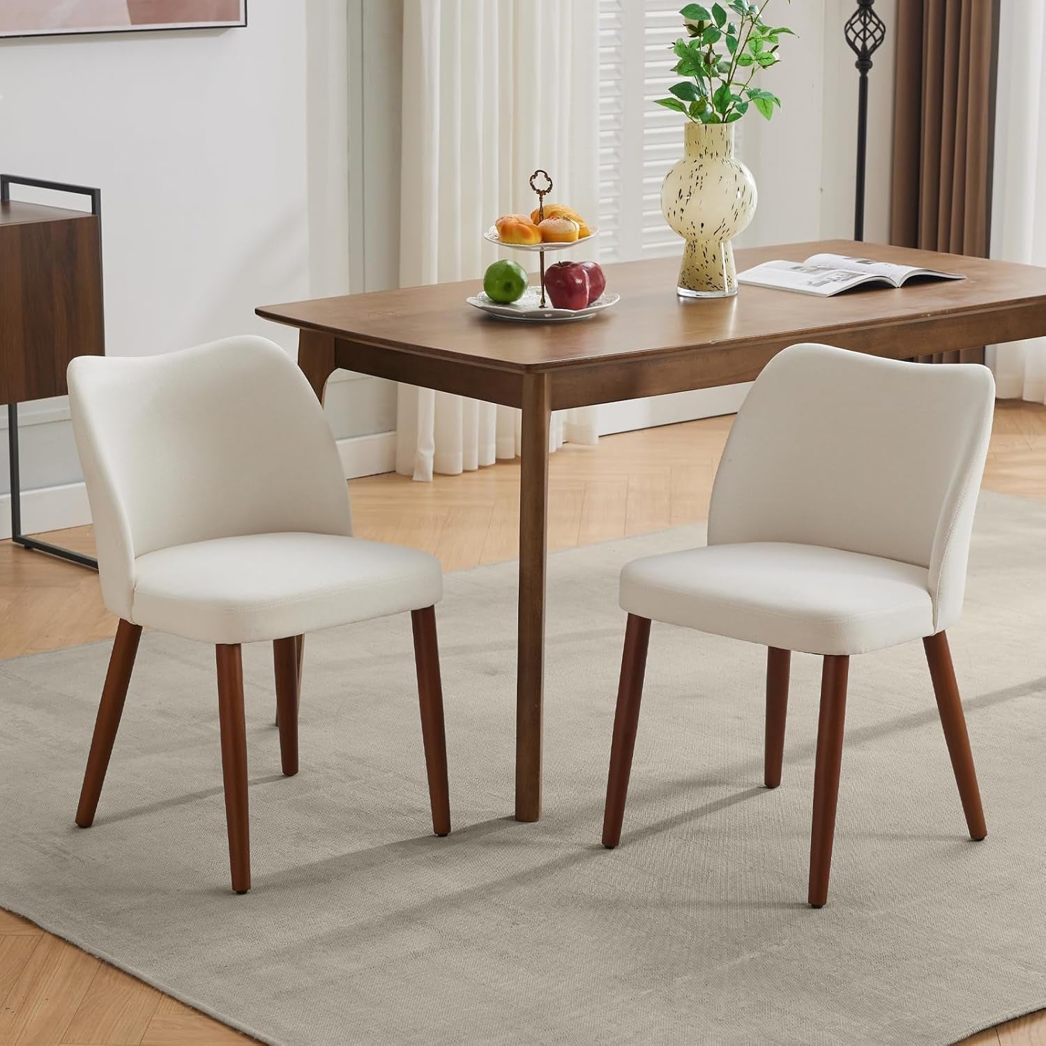 Dining table with two chairs in a room with curtains and a rug.