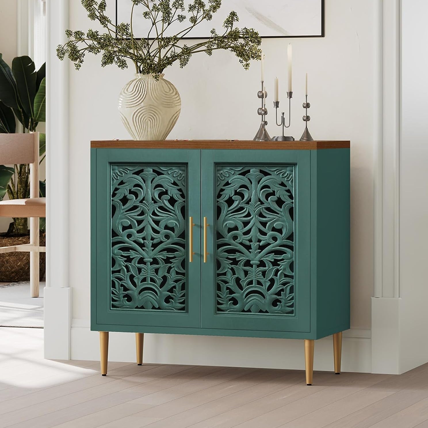 Teal cabinet with decorative patterns in a room with plants and a chair.
