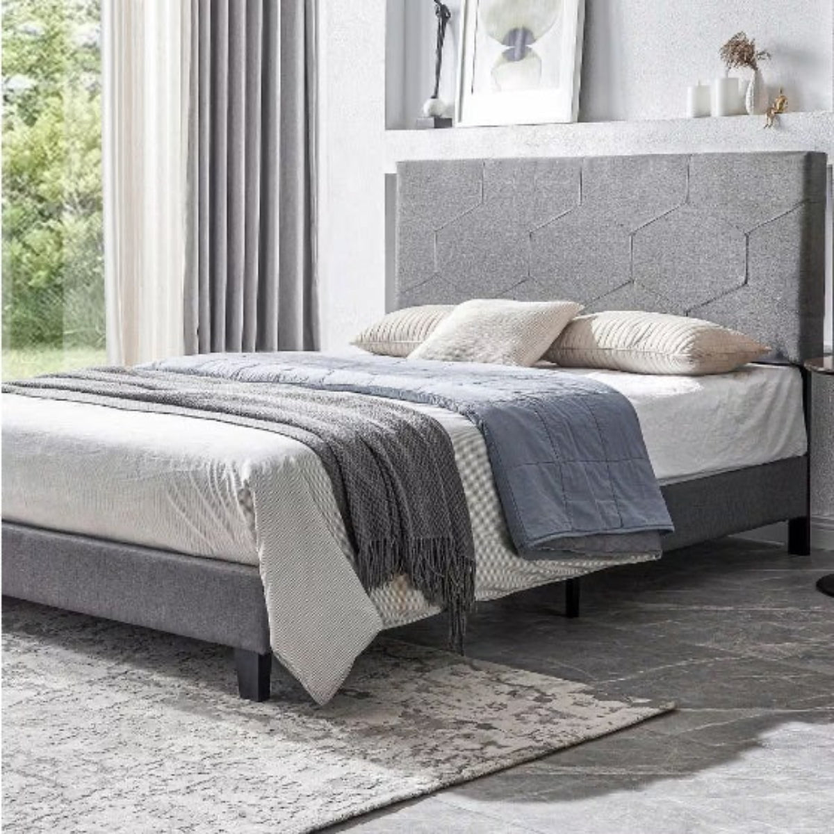 Gray upholstered bed with bedding in a bedroom setting