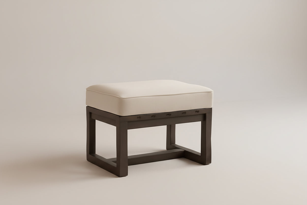 Wooden stool with a cushioned seat in a room with an orange wall and wooden furniture.