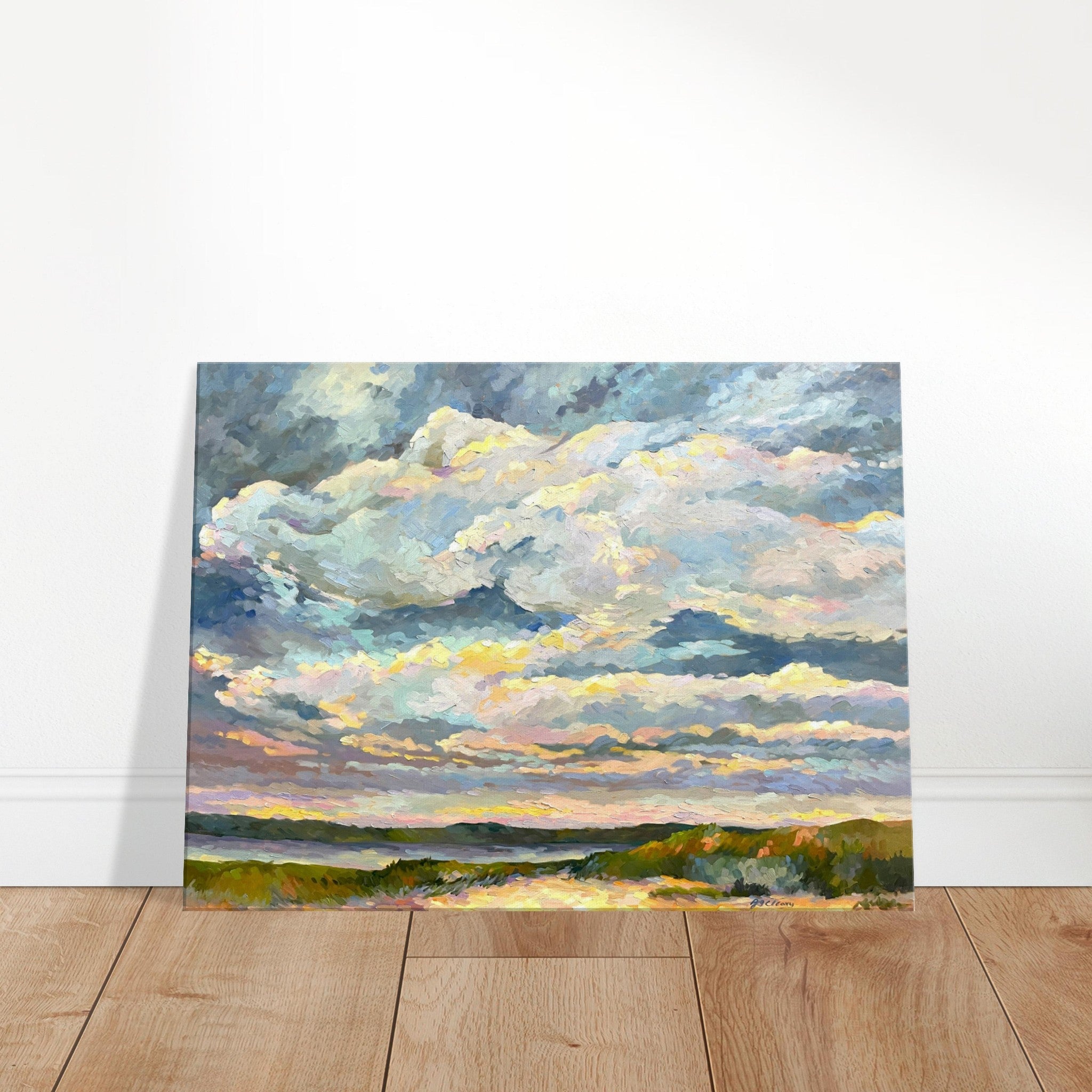 Painting of a landscape with clouds on a wooden floor against a white wall