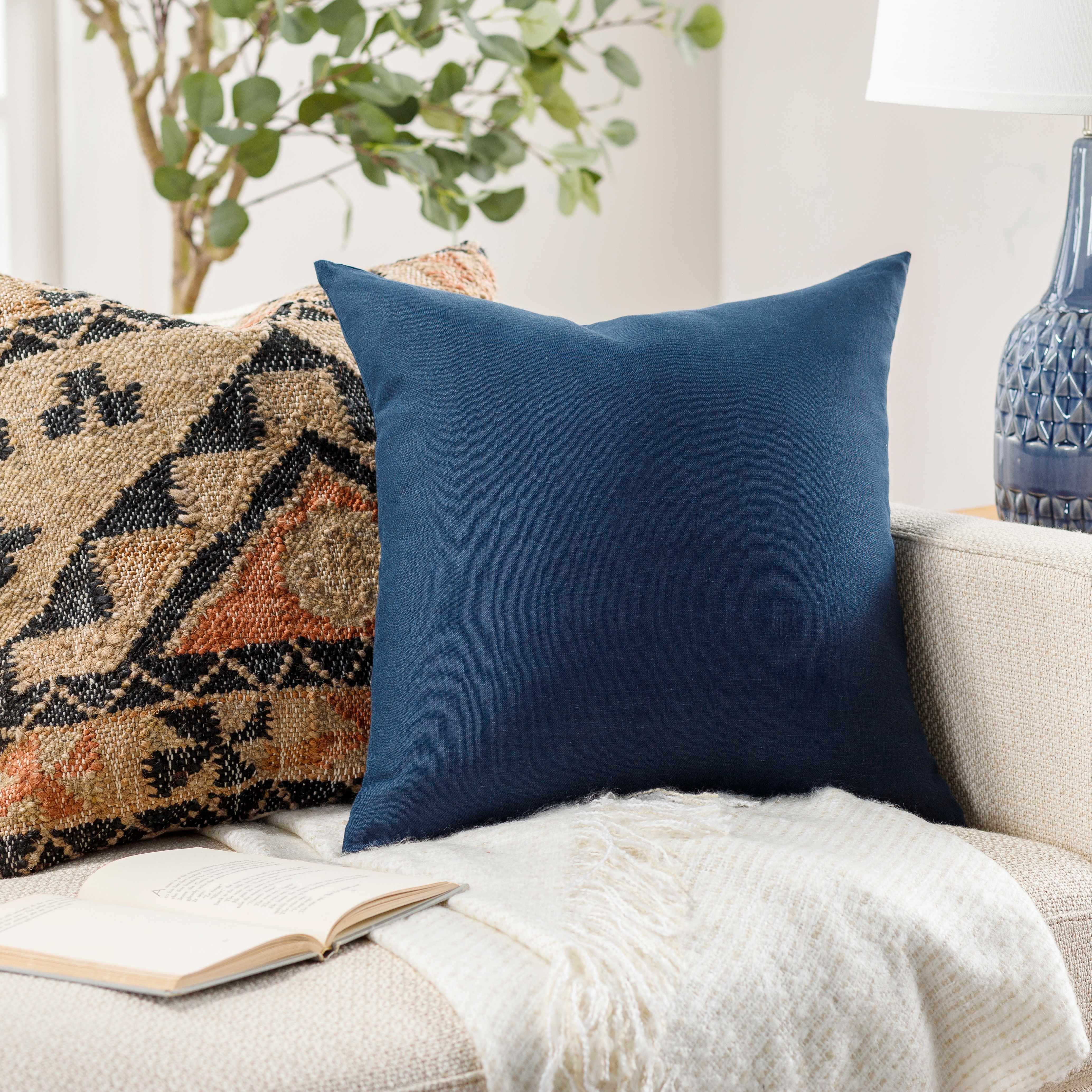 Blue pillow on a couch with a patterned rug and plant in the background