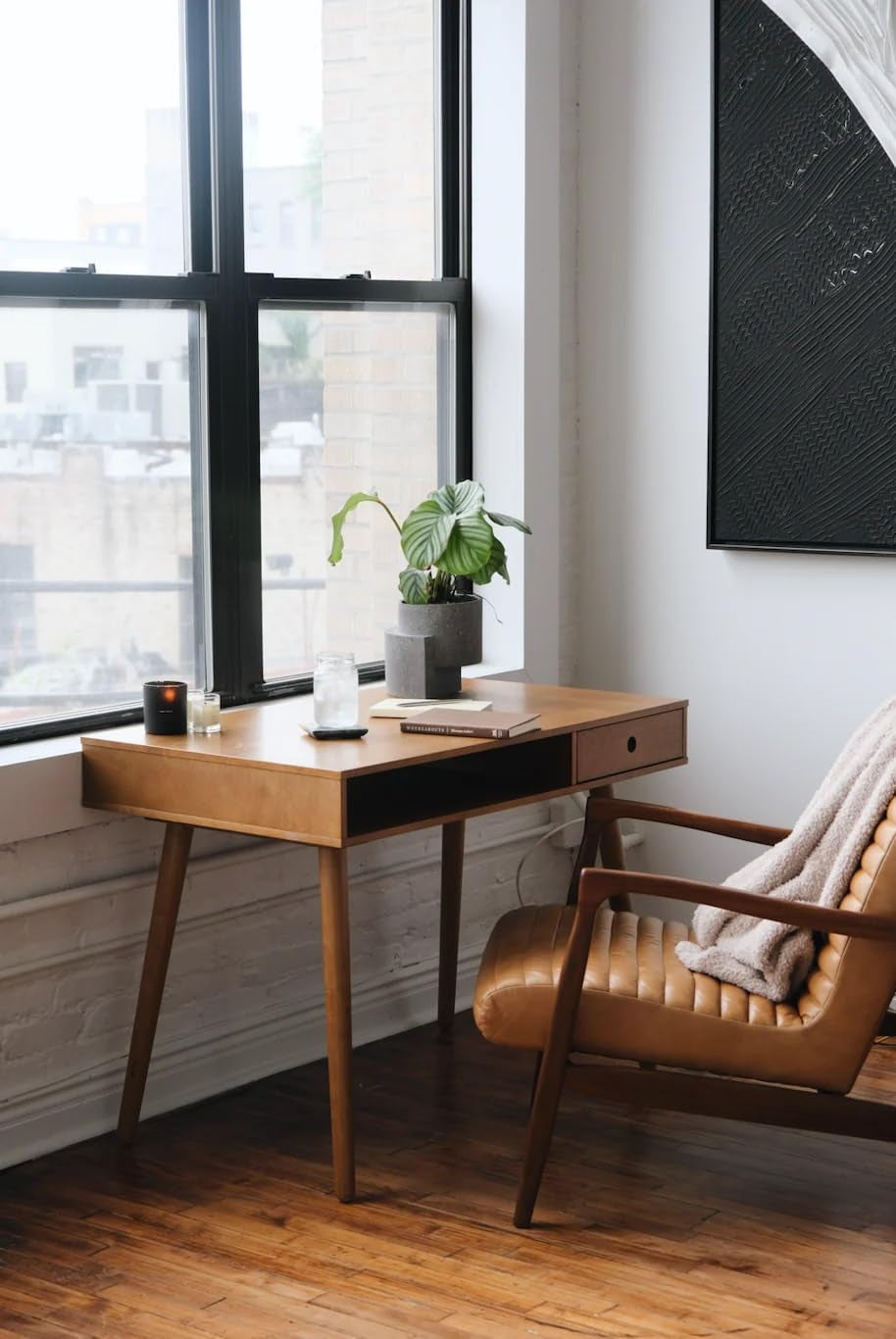 Modern office setup with wooden desk, leather chair, and large window.