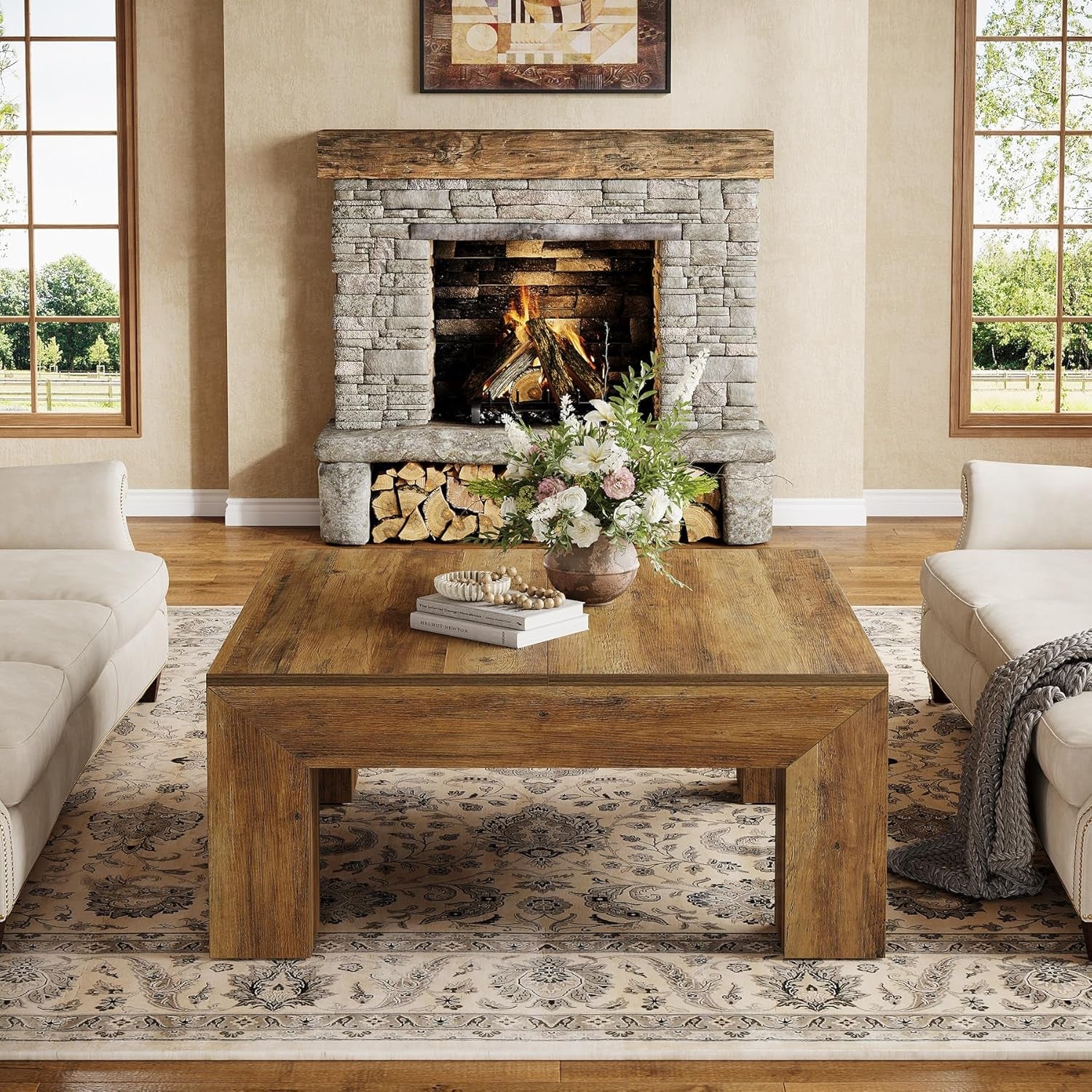 Living room with stone fireplace, wooden coffee table, and white sofas.
