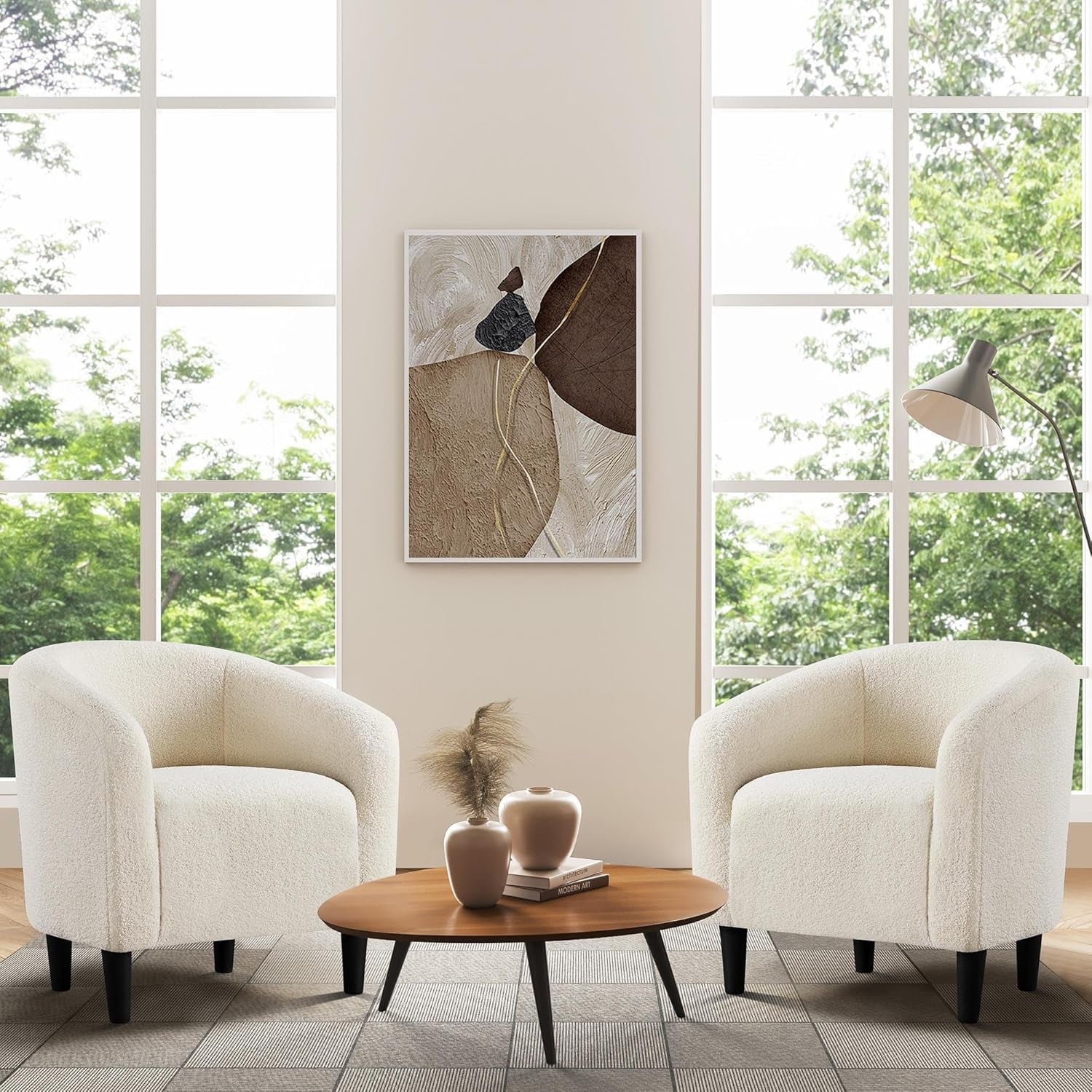 Modern living room with two white armchairs, a wooden coffee table, and abstract art on the wall.