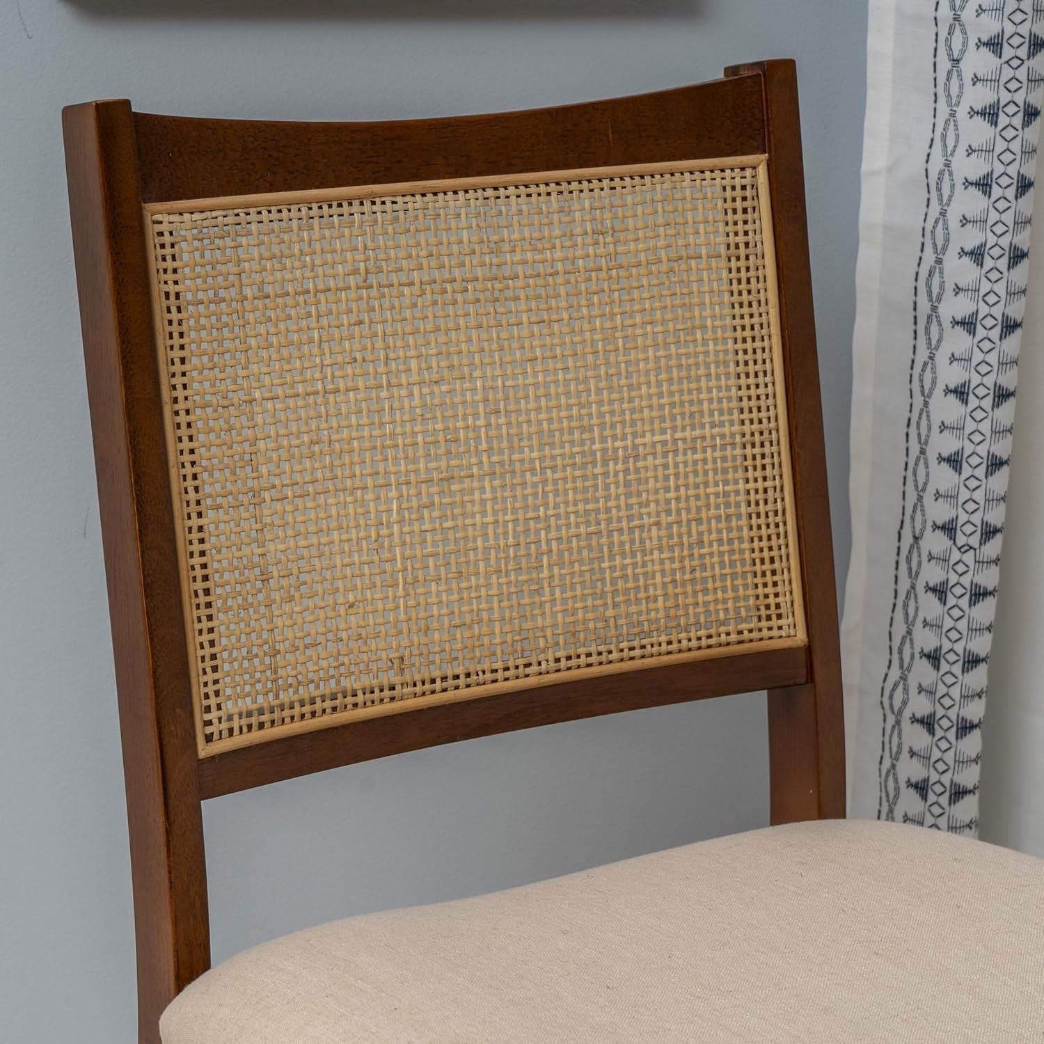 Wooden chair with wicker backrest against a gray wall