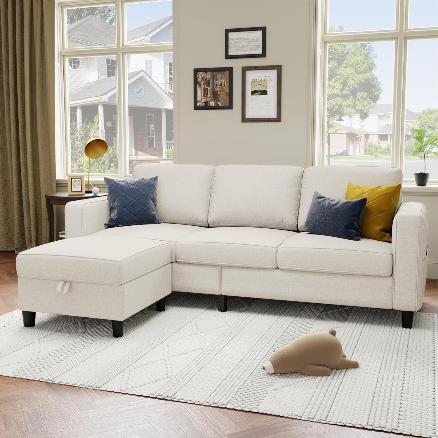 White sectional sofa in a living room with decorative pillows and a teddy bear on a rug.