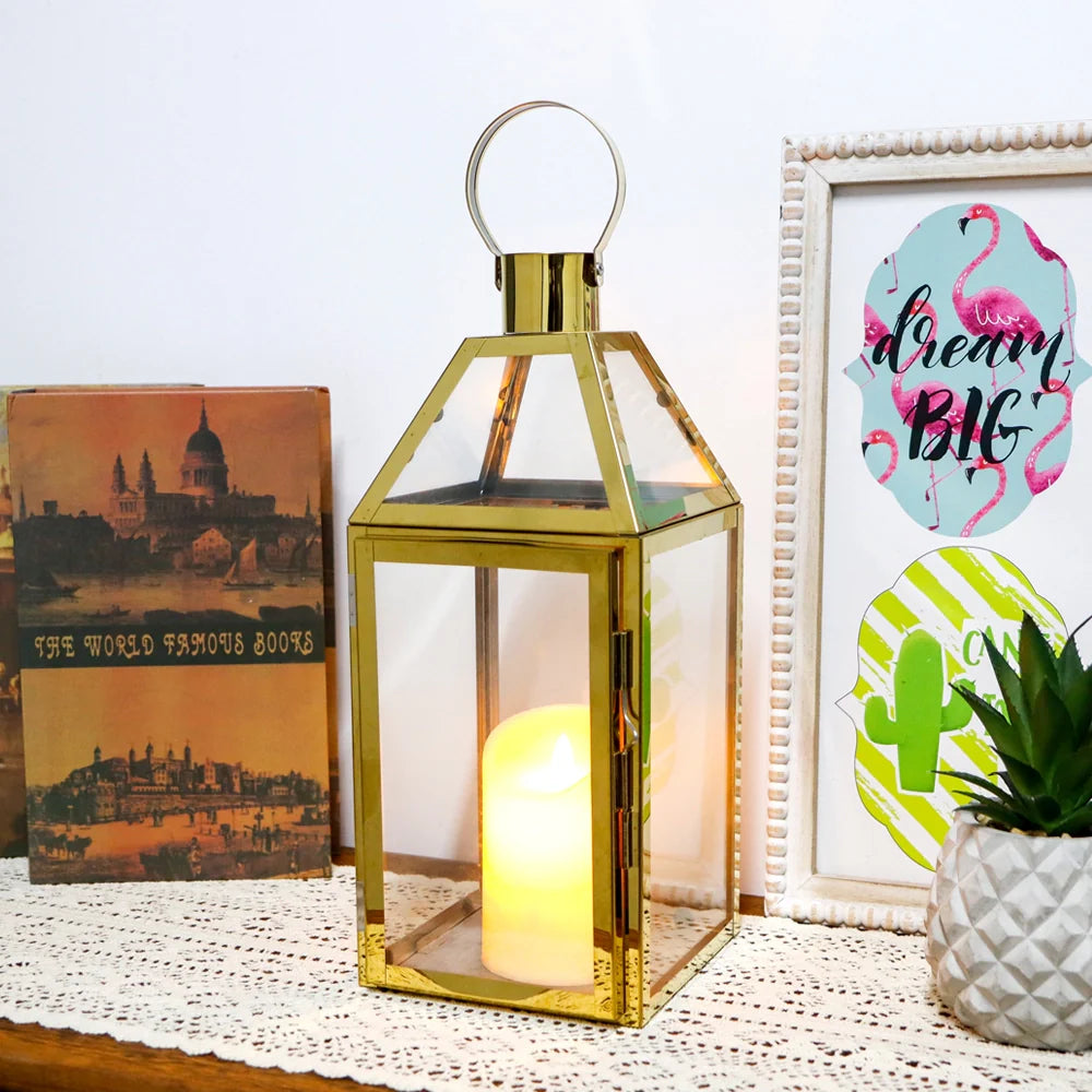 Gold lantern with a lit candle on a table with decorative items
