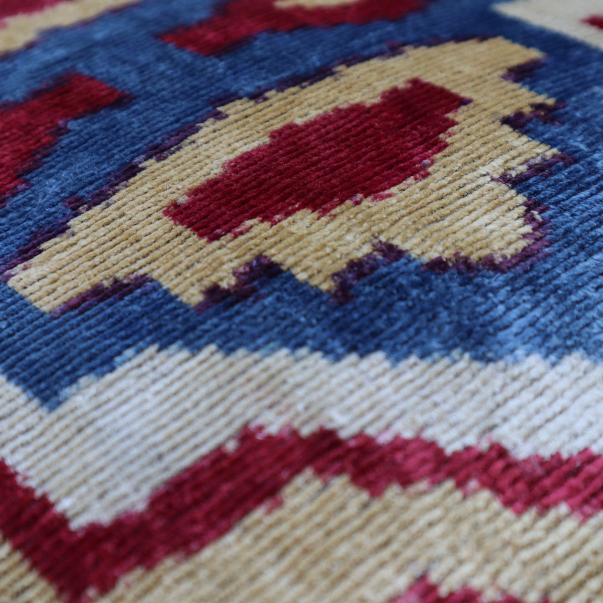 Close-up of a patterned fabric with red, blue, and beige colors.