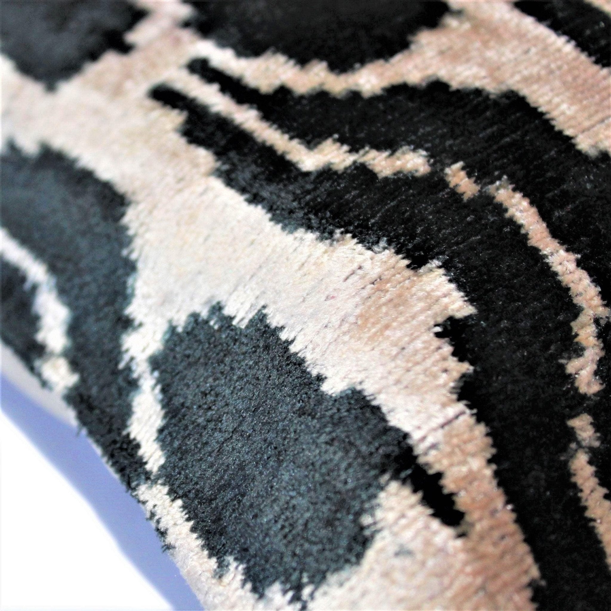 Close-up of a textured fabric with geometric pattern in black, beige, and gray.
