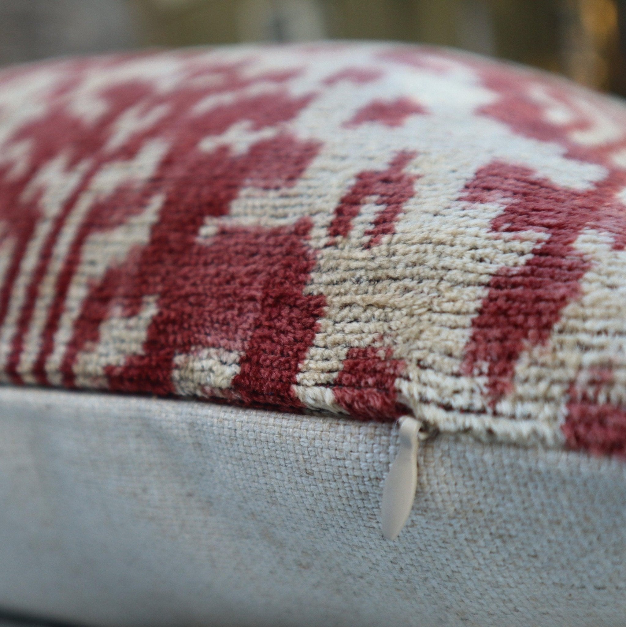 Close-up of a textured fabric with red and beige pattern on a blurred background