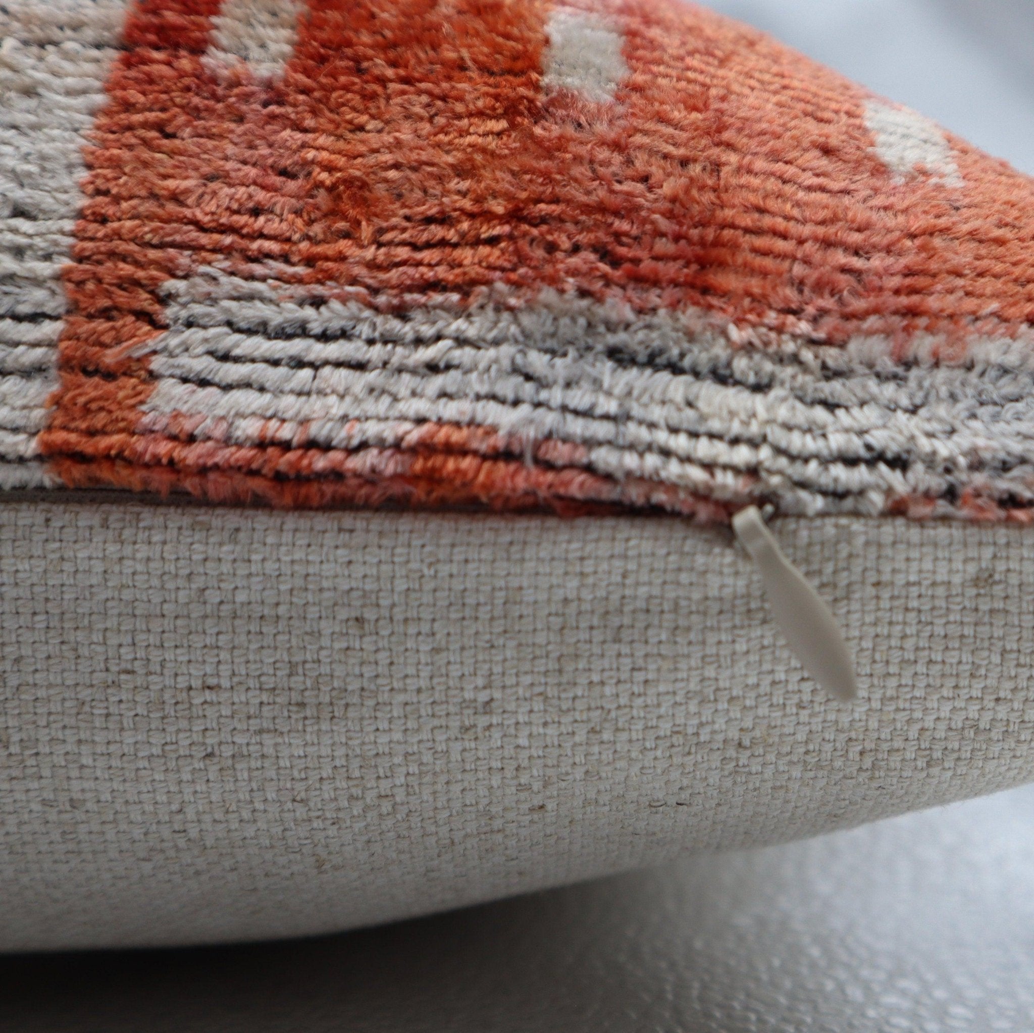 Close-up of a textured fabric with orange and gray pattern on a white background