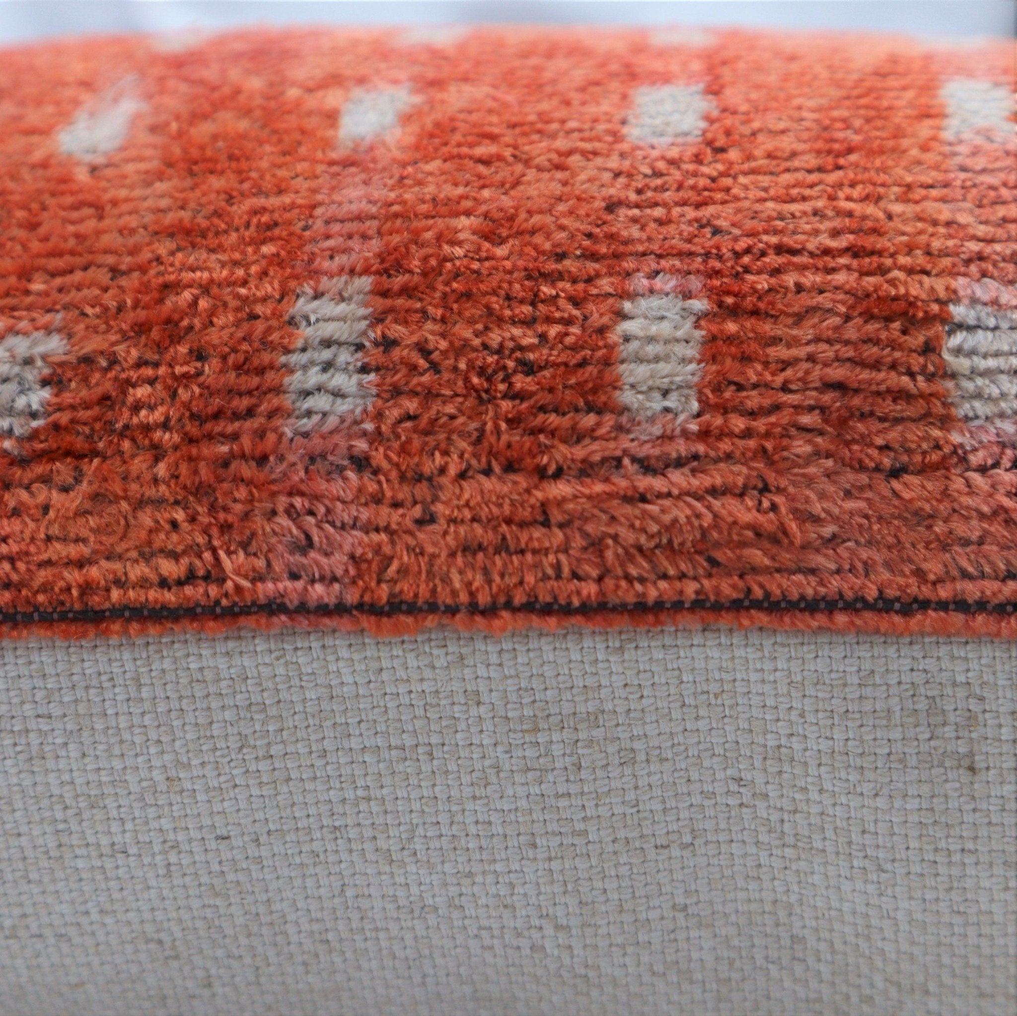 Close-up of a textured orange and beige fabric border on a light gray background