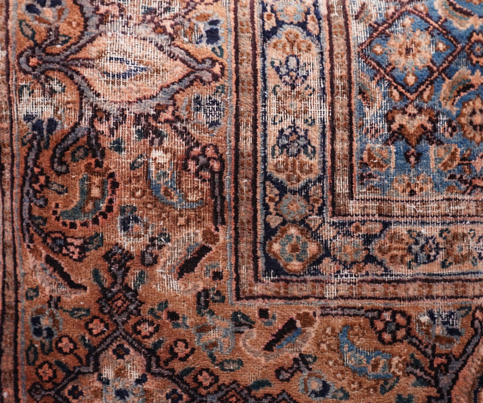 Close-up of an intricately patterned rug with brown, blue, and beige colors.