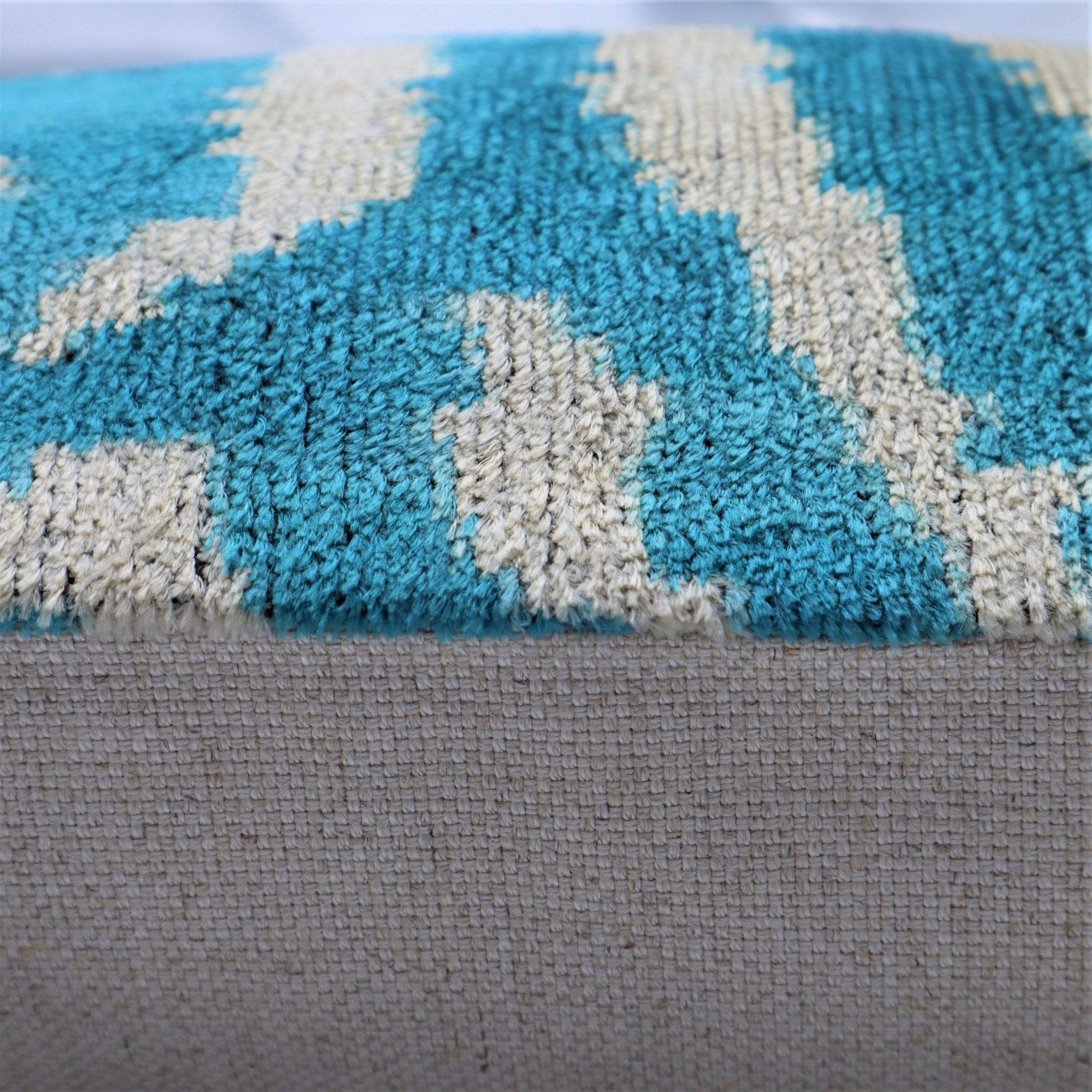 Close-up of a textured blue and beige rug on a gray fabric surface
