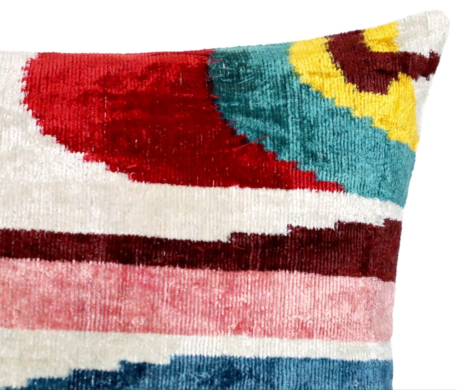 Colorful abstract patterned pillow with red, blue, yellow, and brown colors on a white background.
