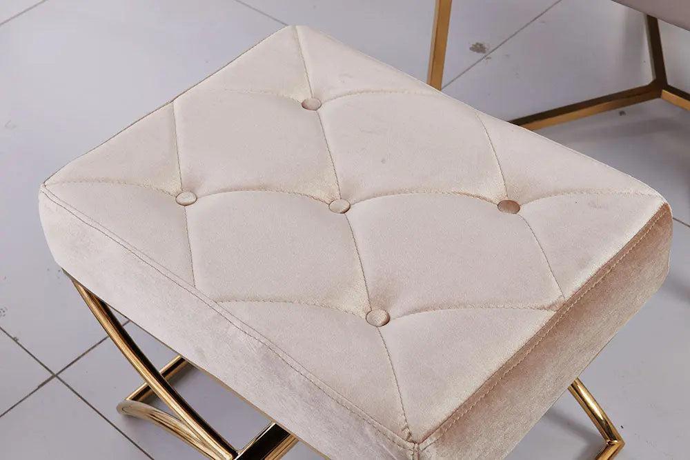Beige tufted ottoman with gold legs on a tiled floor