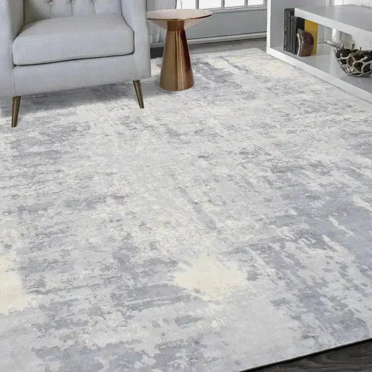 Gray and white patterned rug in a living room setting with a chair and side table.