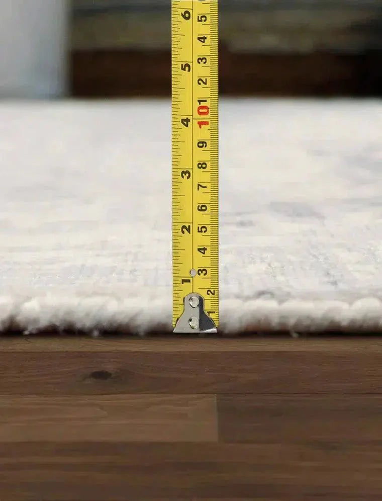 Measuring tape on a rug next to a wooden floor