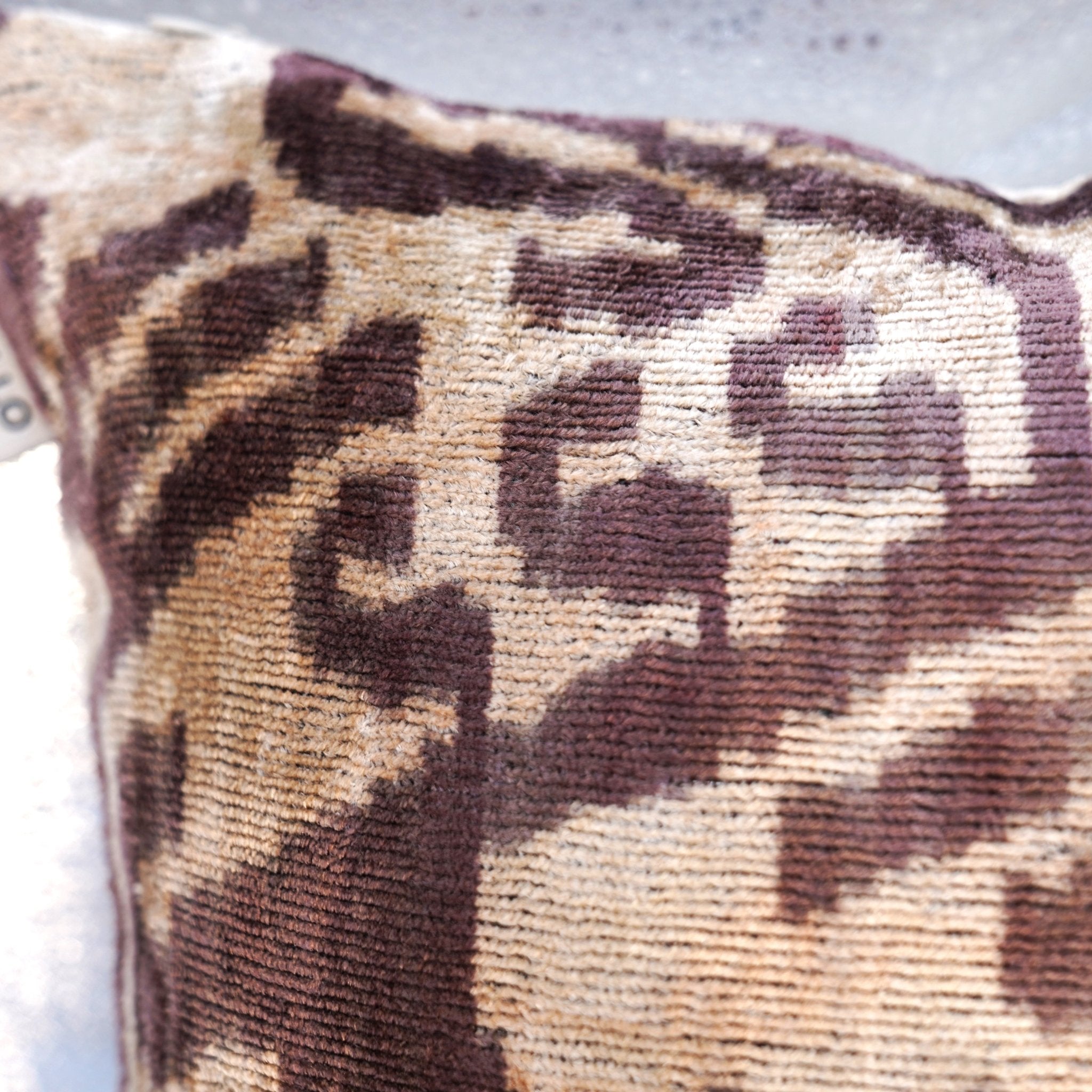 Close-up of a patterned pillow with brown and beige colors on a light background