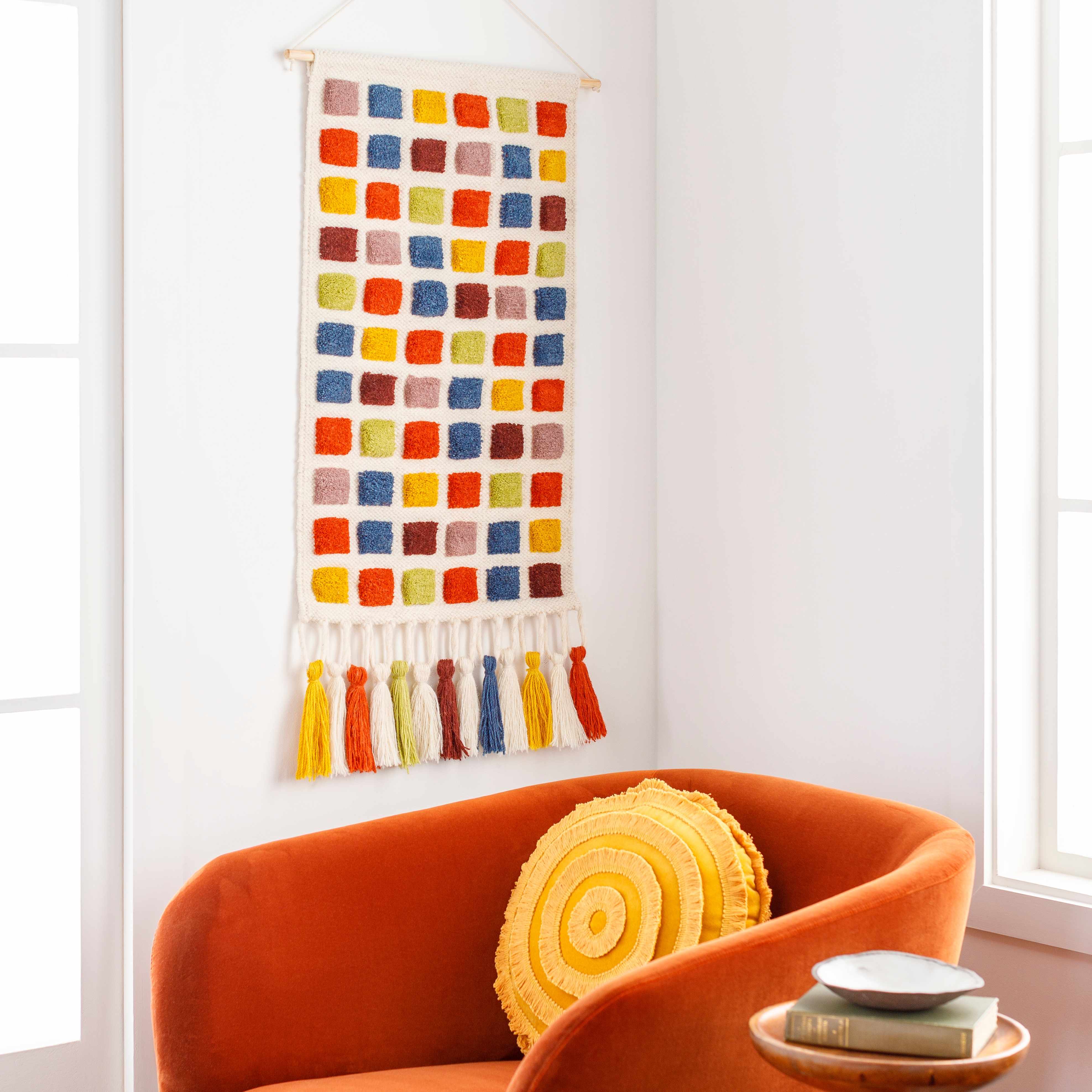 Colorful wall hanging above an orange chair with a yellow pillow