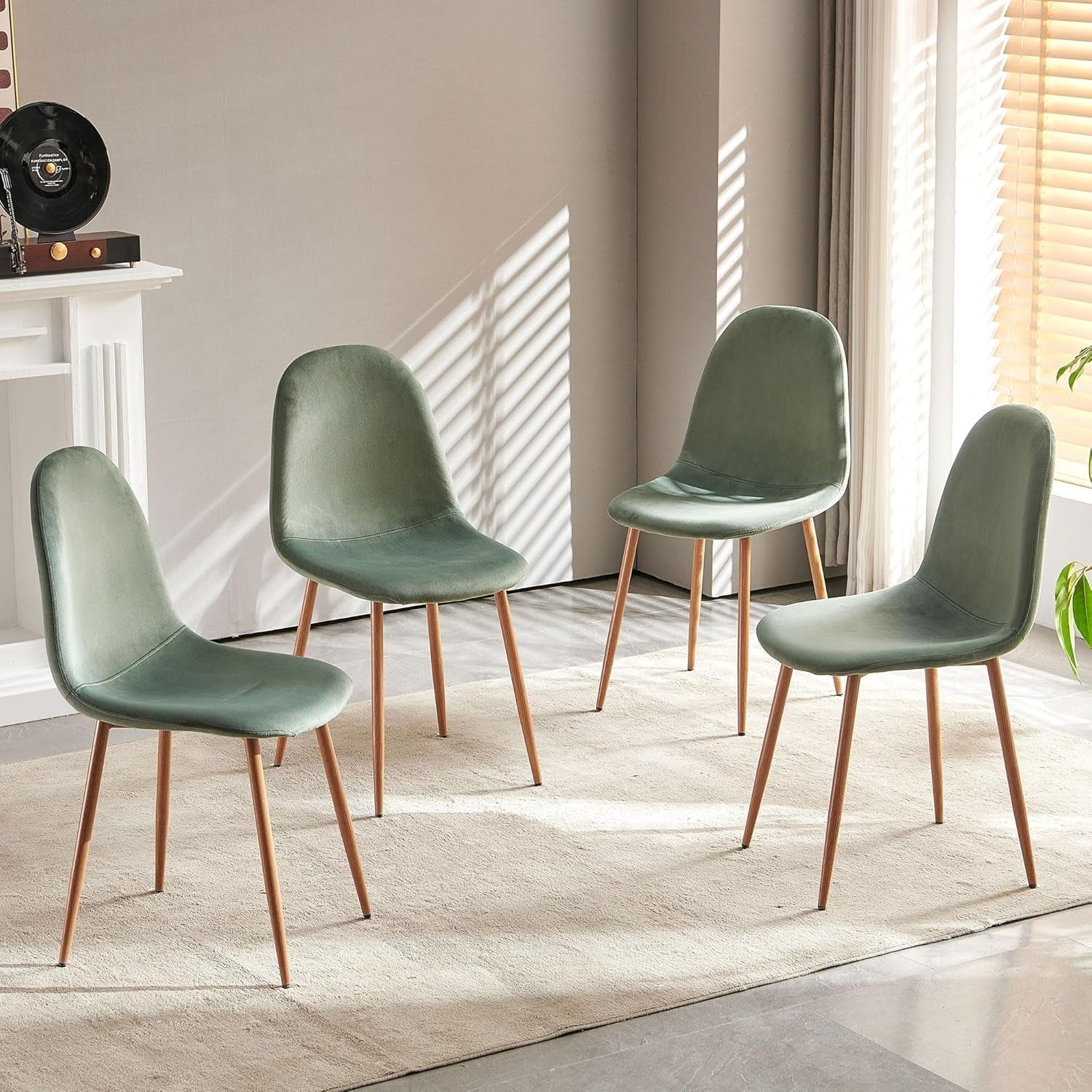 Four green chairs with bronze legs arranged in a room with a neutral color palette.