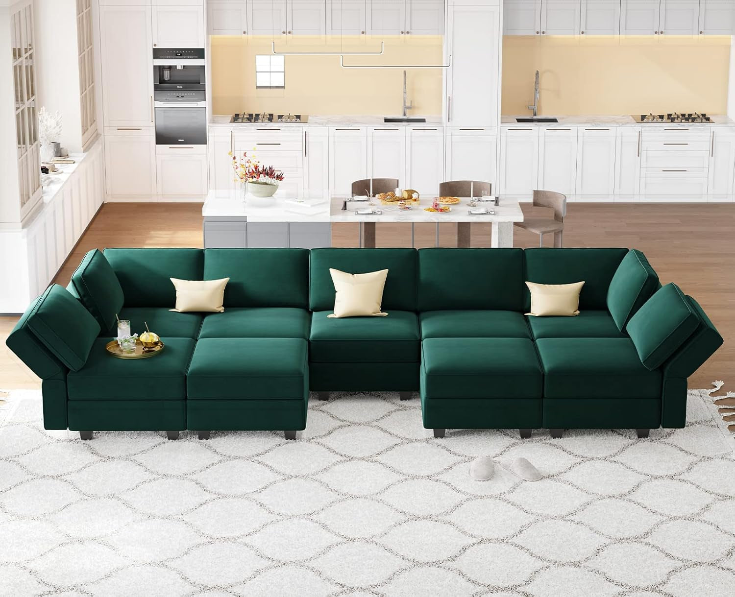 Green sectional sofa in a modern living room with kitchen in the background