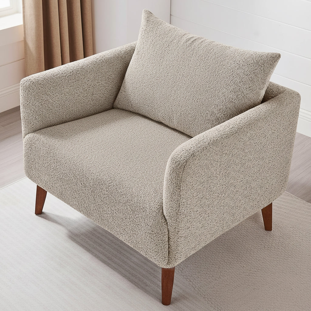 Person sitting on a beige armchair reading a magazine in a bright room.