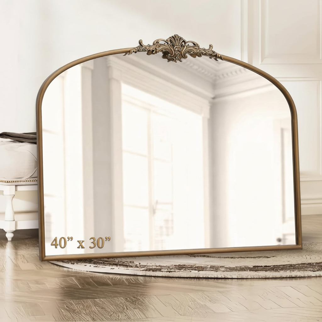 Decorative wall mirror with an ornate frame in a room with wooden flooring and white walls.